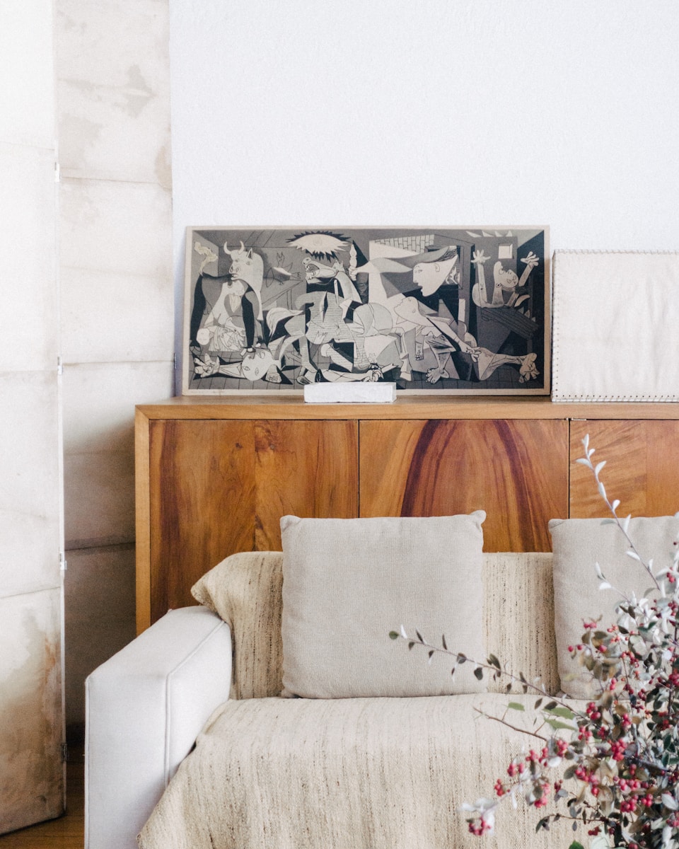 Image d'un salon chic et cosy avec des tons neutres et un canapé en lin beige. Un dos de canapé en bois accessoirisé de cadres pour créer une ambiance chic et cosy