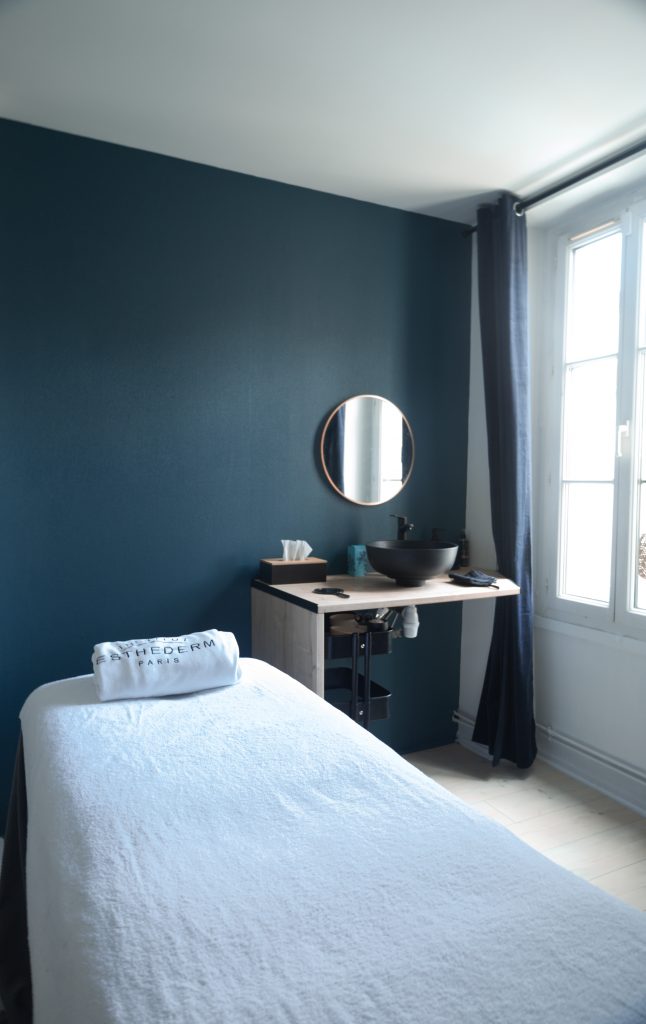 Cabine de soin décorée en bleu profond et noir, ambiance élégante et moderne dans l’institut de beauté 77