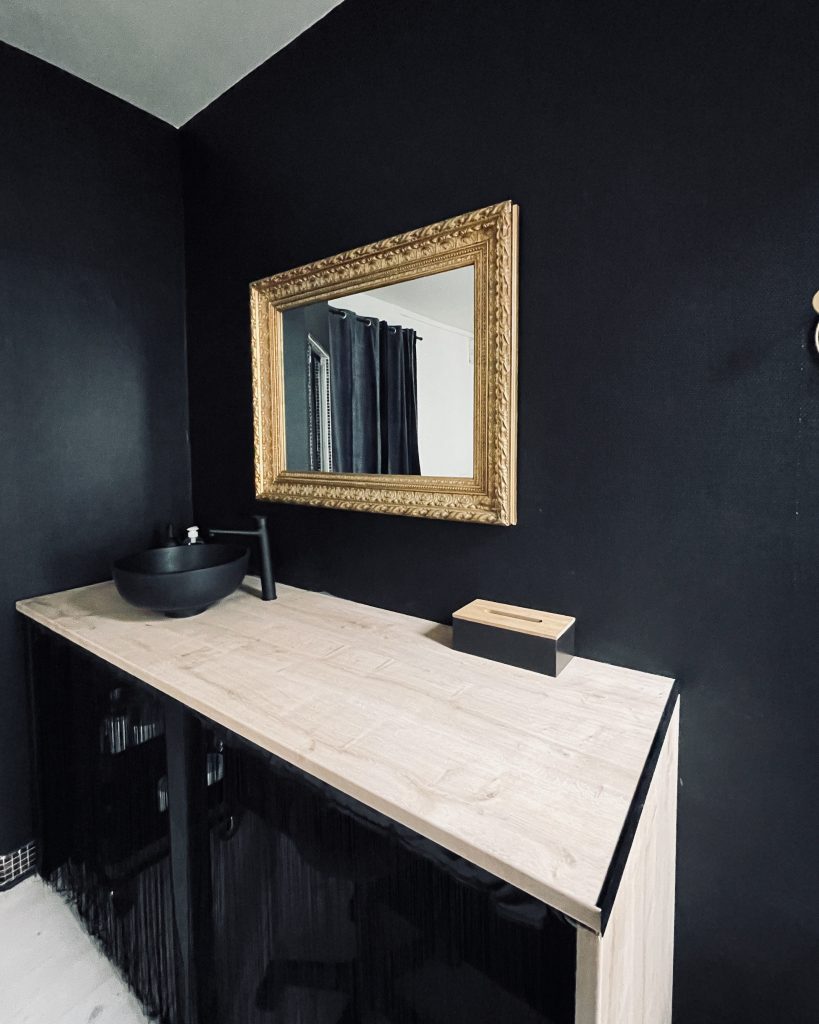 Cabine de soins chic en noir et or, avec détails dorés et ambiance raffinée